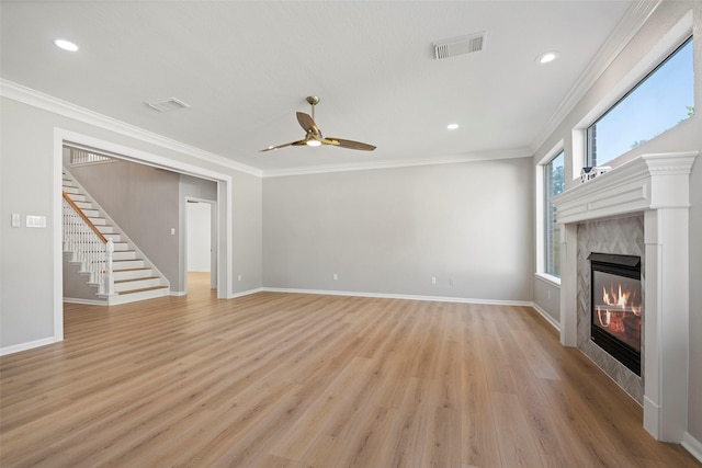 unfurnished living room with ceiling fan, light wood-type flooring, crown molding, and a tiled fireplace