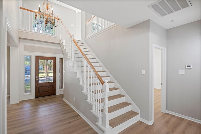 foyer with light hardwood / wood-style flooring, a high ceiling, and a notable chandelier