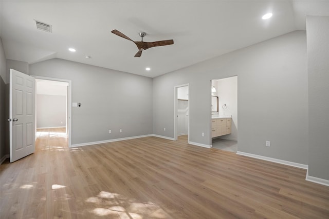 unfurnished bedroom featuring ensuite bath, ceiling fan, a spacious closet, light hardwood / wood-style floors, and vaulted ceiling