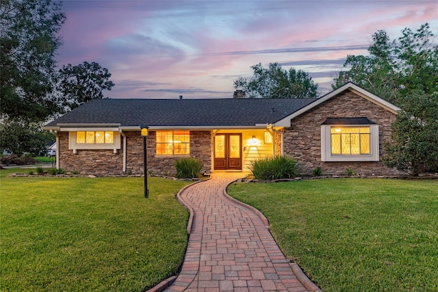 ranch-style house with french doors and a lawn