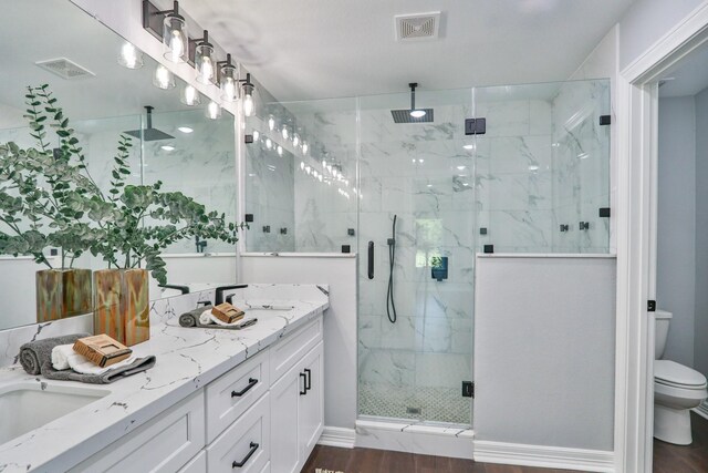 bathroom with hardwood / wood-style floors, vanity, toilet, and walk in shower