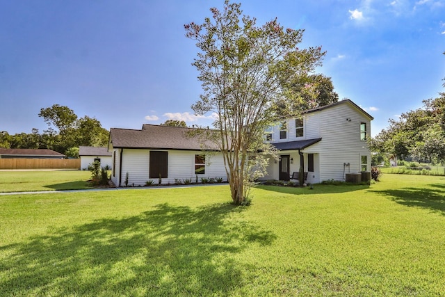 rear view of house with central AC and a yard