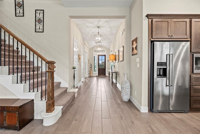 foyer entrance with vaulted ceiling and an inviting chandelier