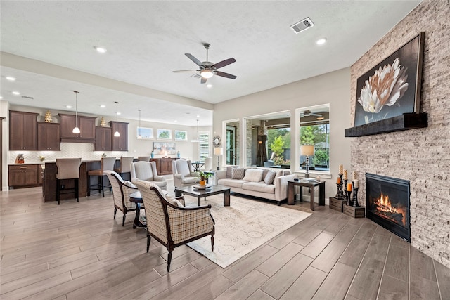 living room with a textured ceiling, plenty of natural light, ceiling fan, and a fireplace