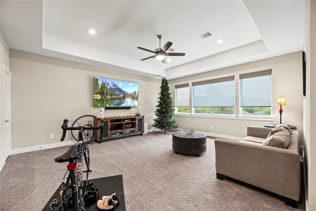 living room featuring carpet floors, a tray ceiling, and ceiling fan