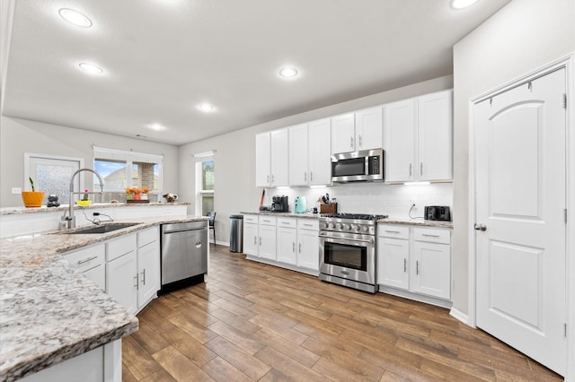 kitchen with light stone countertops, white cabinetry, and appliances with stainless steel finishes