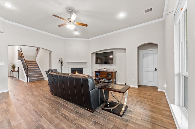 living room with ceiling fan, plenty of natural light, and ornamental molding