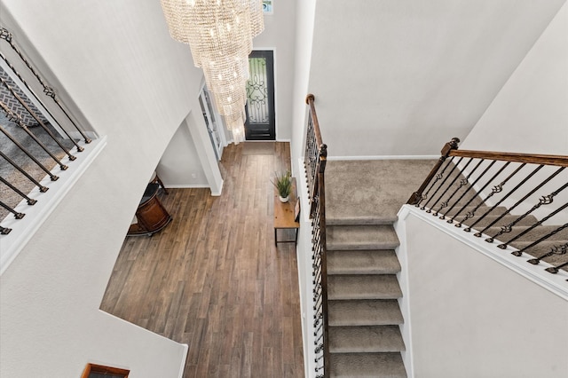 stairs featuring hardwood / wood-style floors and an inviting chandelier