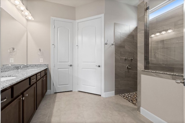 bathroom featuring tile patterned flooring, a tile shower, and vanity