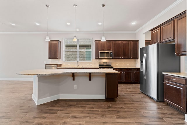 kitchen featuring a kitchen bar, a kitchen island, stainless steel appliances, and decorative light fixtures