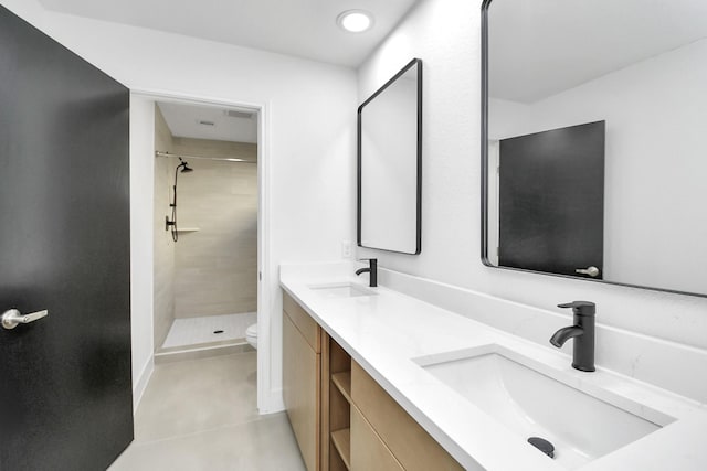 bathroom with tiled shower, vanity, toilet, and tile patterned flooring