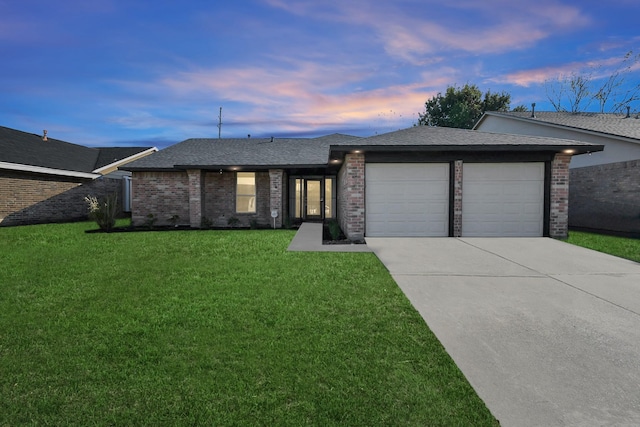 single story home featuring a garage and a lawn