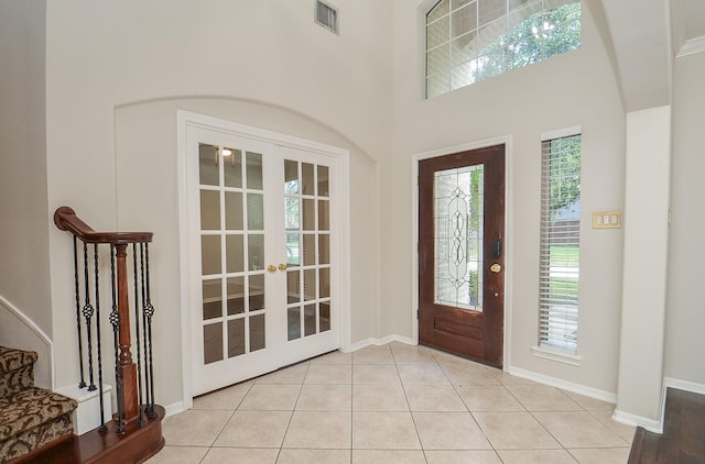 tiled entryway with french doors, a wealth of natural light, and a high ceiling