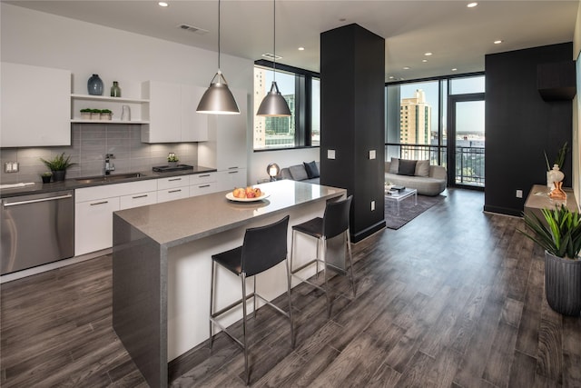 kitchen with dishwasher, a wall of windows, white cabinetry, and sink