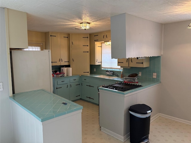 kitchen featuring sink, decorative backsplash, kitchen peninsula, and white fridge