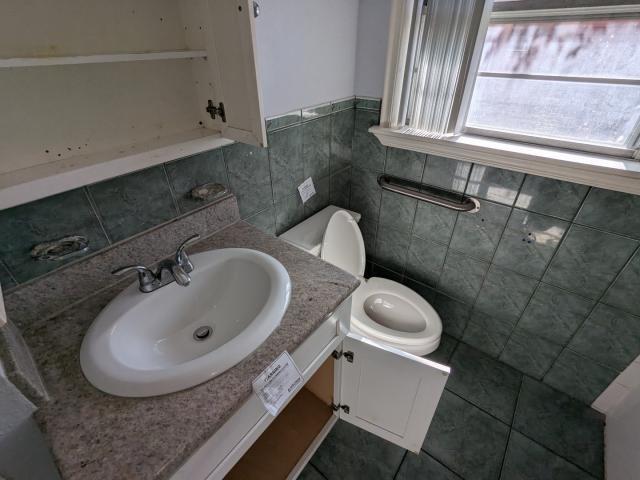 bathroom with tile patterned floors, vanity, toilet, and tile walls