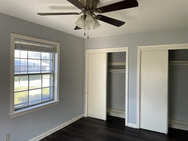 unfurnished bedroom with multiple windows, two closets, and ceiling fan