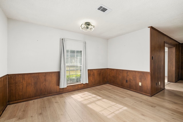 unfurnished room with light hardwood / wood-style floors and a textured ceiling