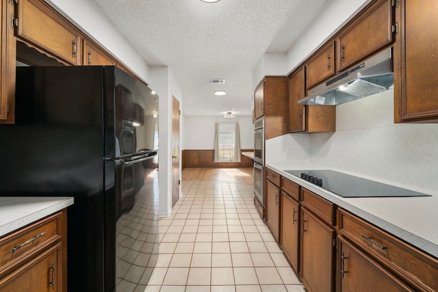 kitchen featuring a textured ceiling, black appliances, and light tile patterned flooring