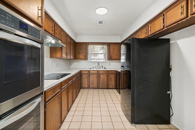 kitchen with a textured ceiling, light tile patterned floors, sink, and black appliances