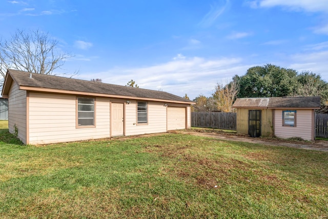 rear view of property with a garage, a yard, and an outdoor structure