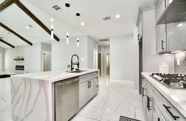 kitchen with stainless steel appliances, tasteful backsplash, an island with sink, decorative light fixtures, and exhaust hood