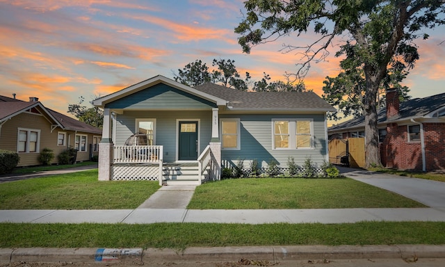 bungalow-style home with covered porch and a yard