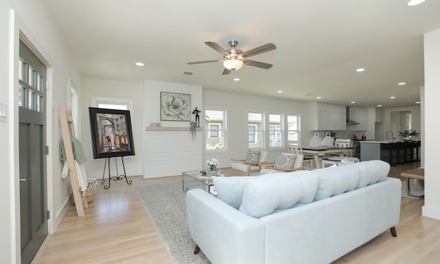 living room with light hardwood / wood-style flooring and ceiling fan