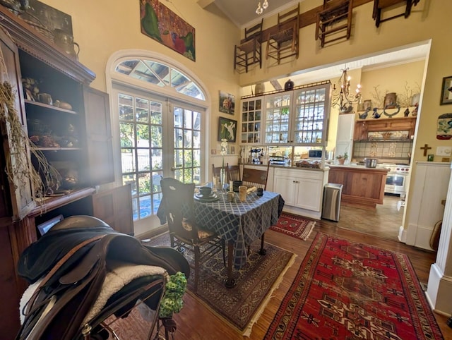 dining area with a high ceiling, dark hardwood / wood-style floors, french doors, and ornamental molding