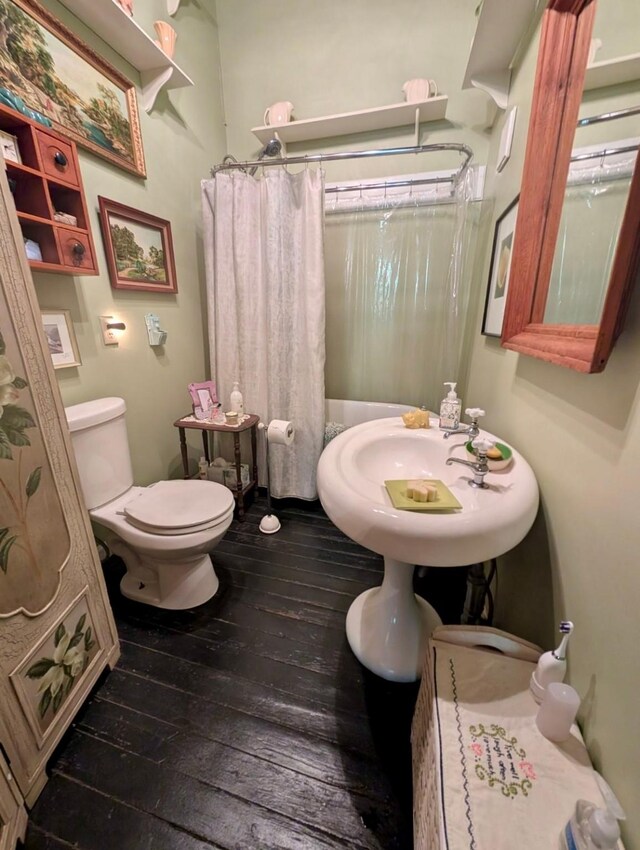 bathroom with wood-type flooring, toilet, a shower with curtain, and sink