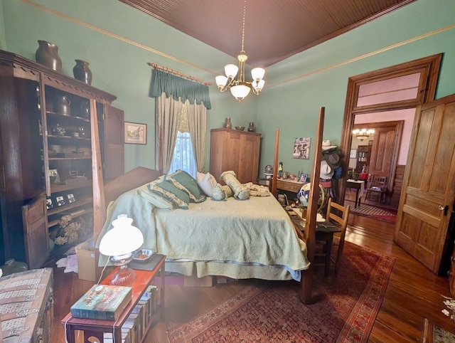 bedroom with dark hardwood / wood-style floors and an inviting chandelier