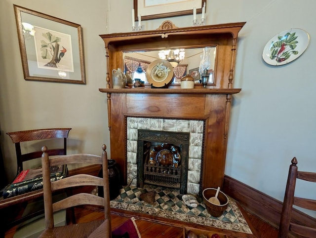 sitting room featuring a fireplace, wood-type flooring, and a chandelier