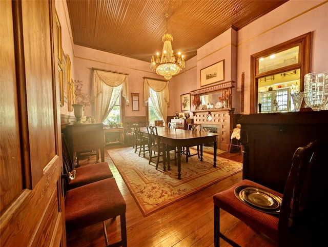 sitting room featuring a tiled fireplace, a chandelier, wood-type flooring, and wooden ceiling