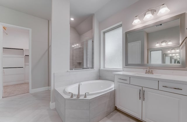 bathroom with vanity and a relaxing tiled tub