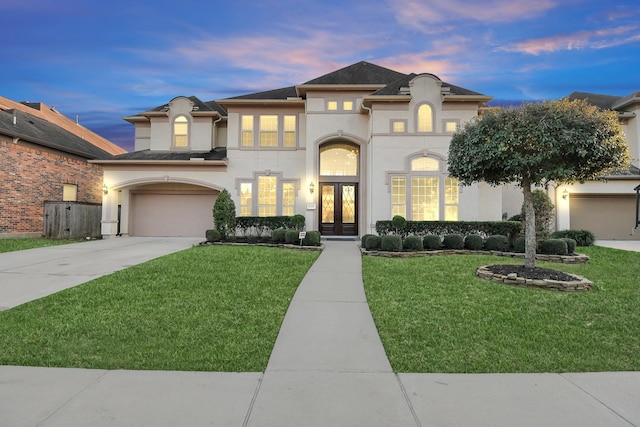 view of front facade featuring french doors, a garage, and a lawn