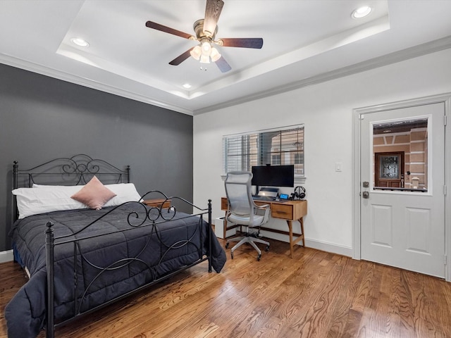 bedroom with ceiling fan, a raised ceiling, light wood-type flooring, and ornamental molding