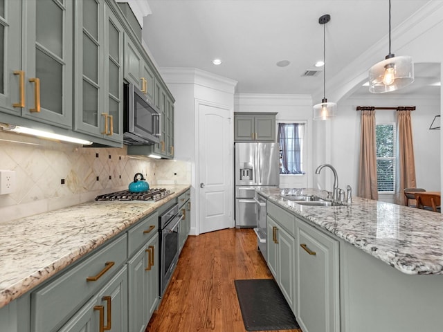 kitchen featuring pendant lighting, a center island with sink, sink, dark hardwood / wood-style floors, and appliances with stainless steel finishes