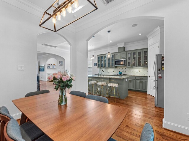 dining room with hardwood / wood-style floors, ornamental molding, and sink