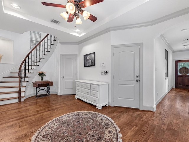 foyer with a tray ceiling, hardwood / wood-style flooring, crown molding, and ceiling fan