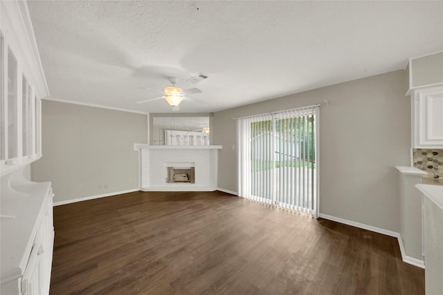 unfurnished living room with a textured ceiling, dark hardwood / wood-style flooring, a brick fireplace, and ceiling fan