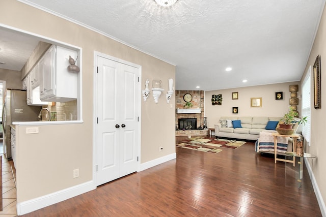 living room featuring hardwood / wood-style floors, a textured ceiling, a brick fireplace, and sink