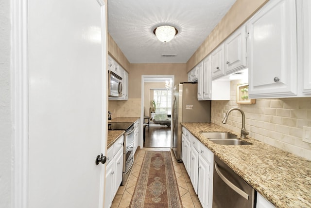 kitchen featuring light stone countertops, stainless steel appliances, sink, white cabinets, and light tile patterned flooring