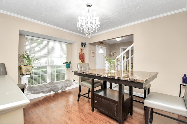 dining area with a chandelier, hardwood / wood-style floors, a textured ceiling, and crown molding