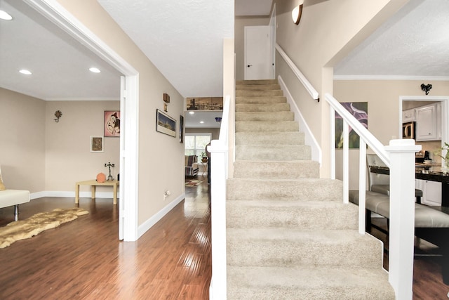 stairs featuring hardwood / wood-style flooring and crown molding