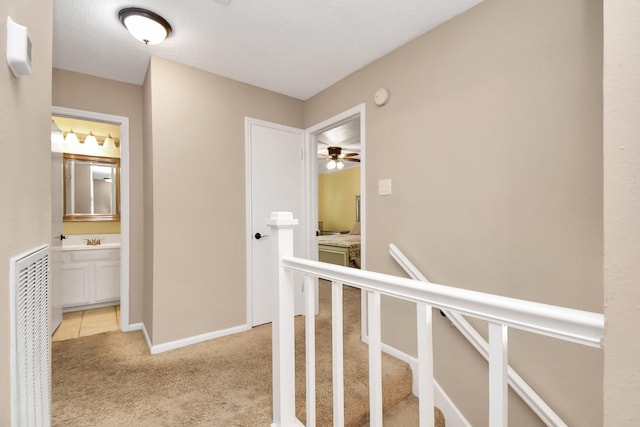 hallway with light carpet and sink