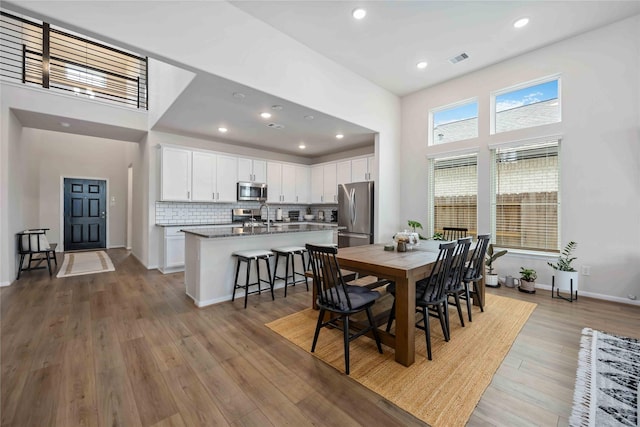 dining room with a high ceiling, hardwood / wood-style flooring, and sink