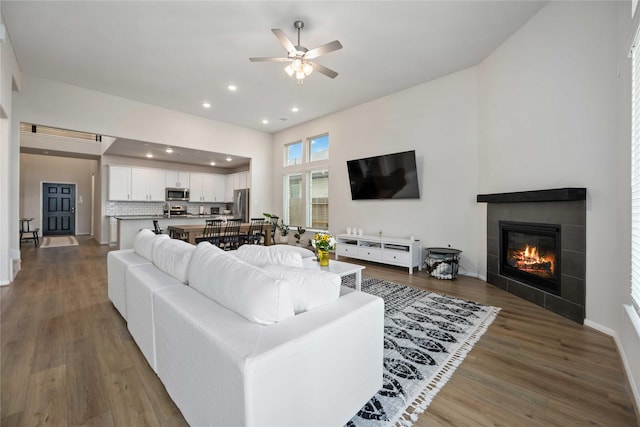 living room featuring ceiling fan, dark hardwood / wood-style floors, and a tile fireplace