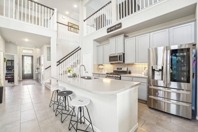 kitchen featuring tasteful backsplash, sink, a towering ceiling, and appliances with stainless steel finishes