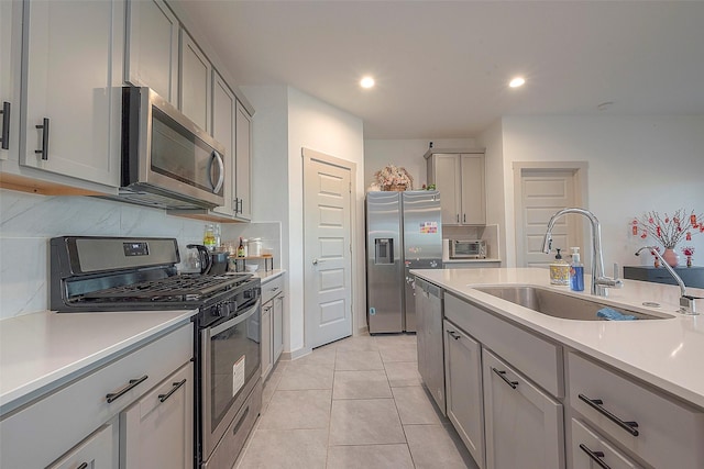 kitchen featuring a sink, light countertops, gray cabinetry, and stainless steel appliances