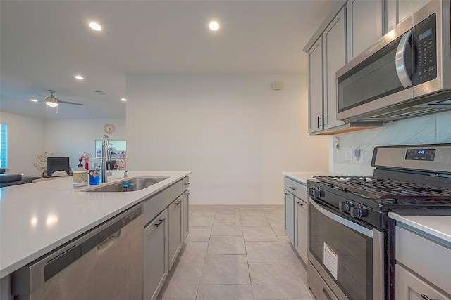 kitchen featuring a sink, backsplash, appliances with stainless steel finishes, and light countertops